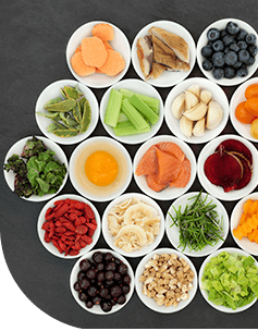 Verschiedene gesunde Lebensmittel in Schalen angeordnet, die eine ausgewogene Ernährung symbolisieren, darunter Gemüse, Beeren und Fisch.