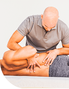 Ein Osteopath behandelt einen Patienten durch manuelle Therapie am Bein, wobei der Patient auf einer Behandlungsliege liegt und entspannt aussieht.